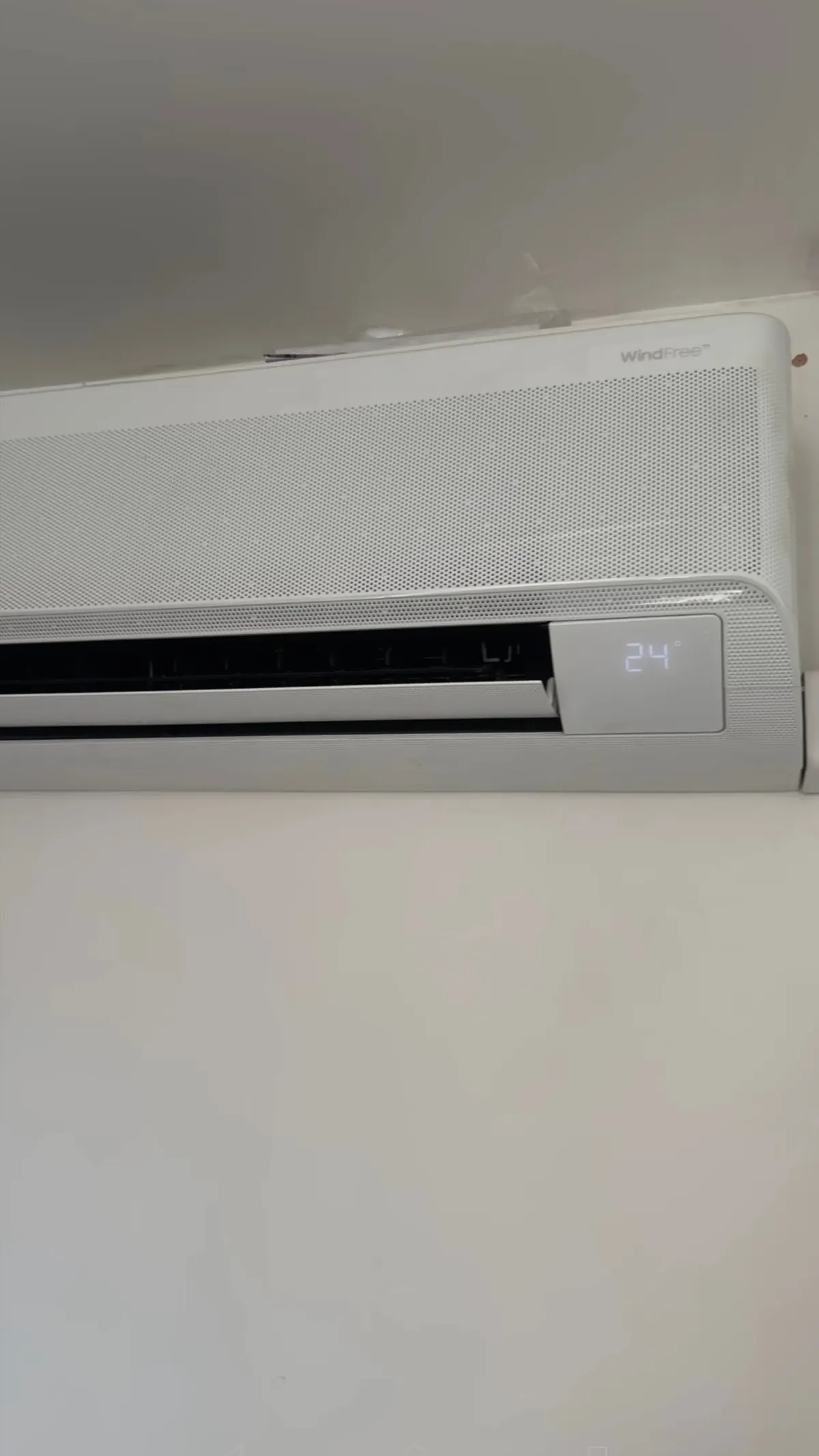 Wall-mounted indoor air conditioning unit showing the set temperature on its display