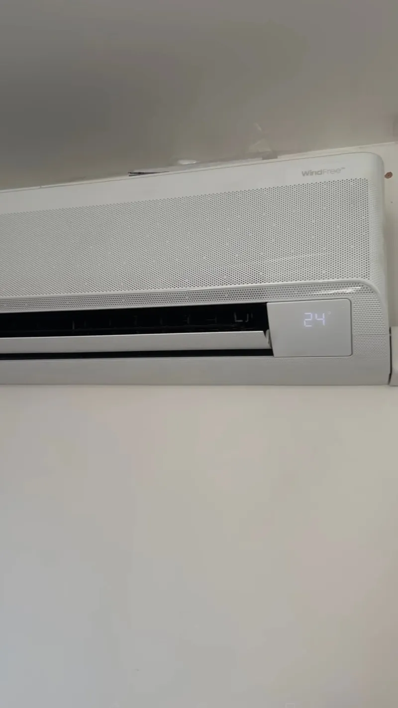 White wall-mounted indoor air conditioning unit showing the set temperature on its display