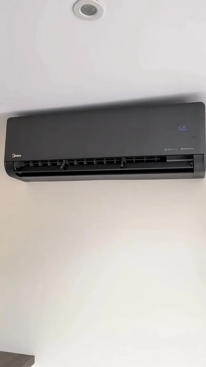 Matte black wall-mounted indoor air conditioning unit with the display lit